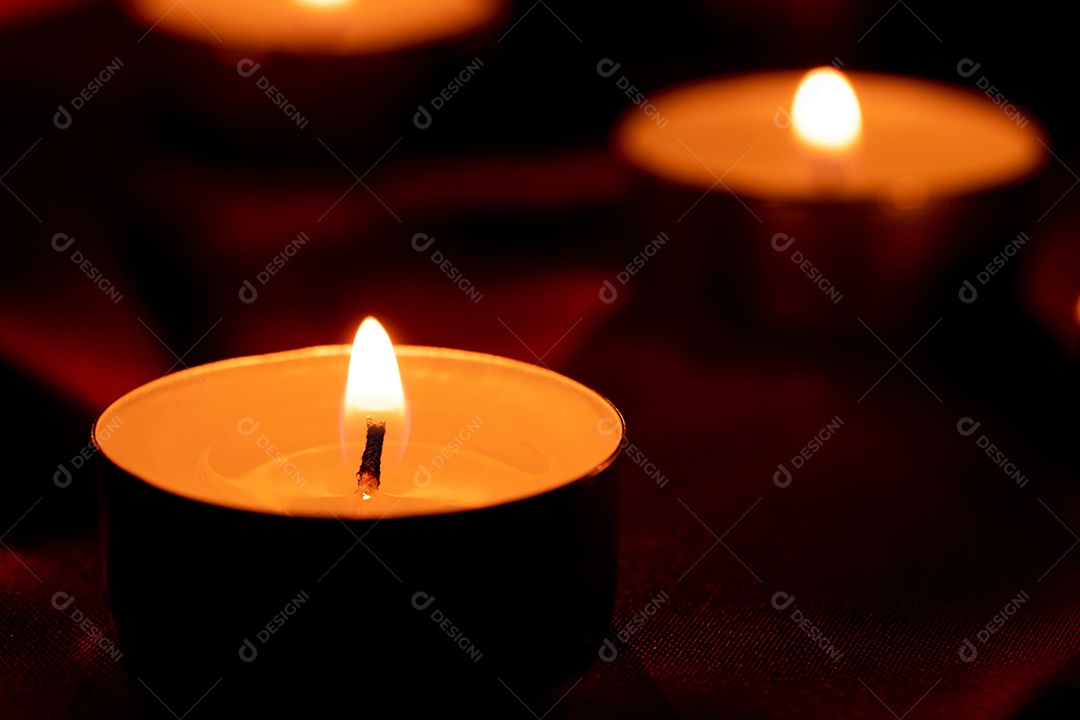 Luz de vela e fundo de tecido vermelho na escuridão