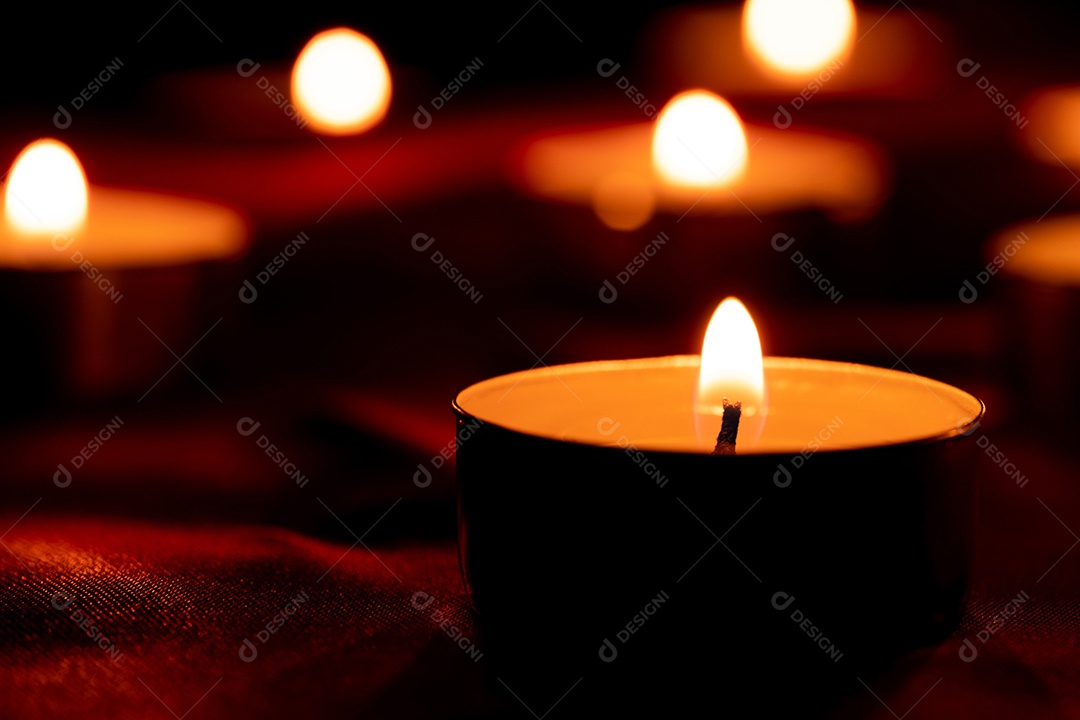 Luz de vela e fundo de tecido vermelho na escuridão