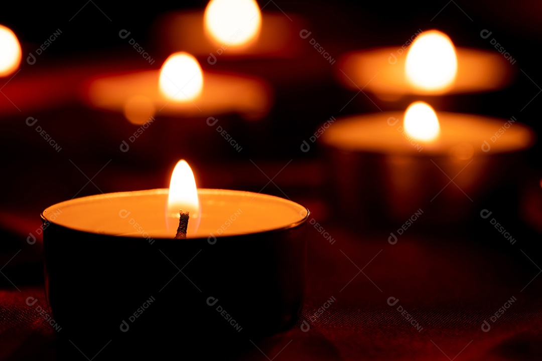 Luz de vela e fundo de tecido vermelho na escuridão