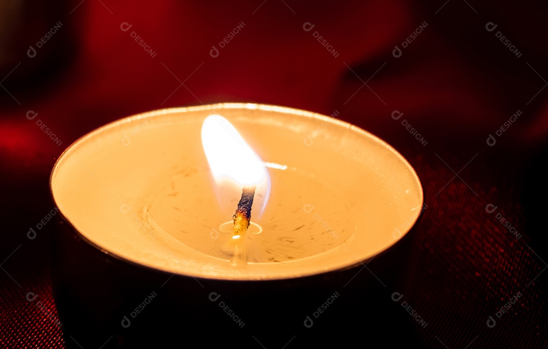 Luz de vela e fundo de tecido vermelho na escuridão