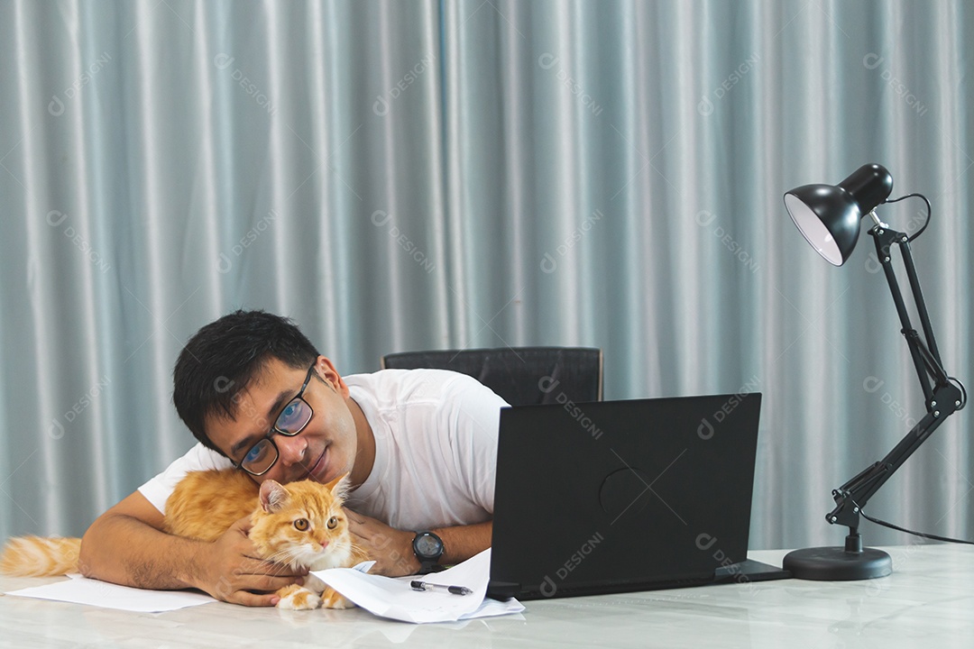 Homem segurando seu gato de estimação sobre escritório mexendo notebook