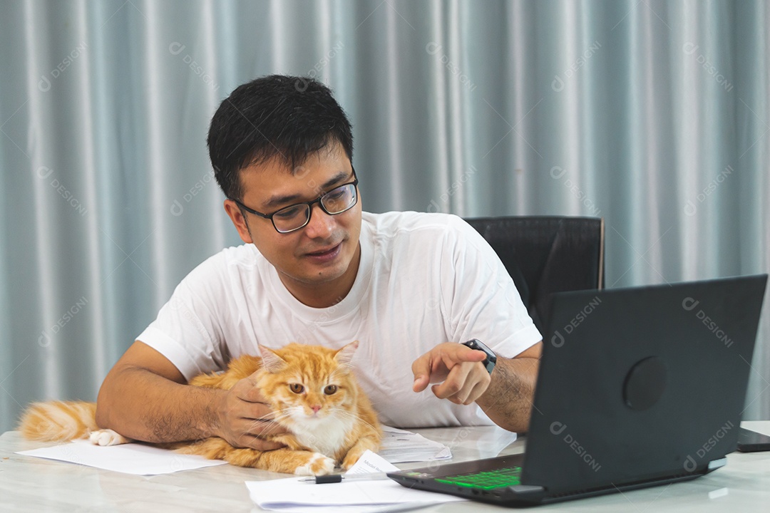 Homem segurando seu gato de estimação sobre escritório mexendo notebook