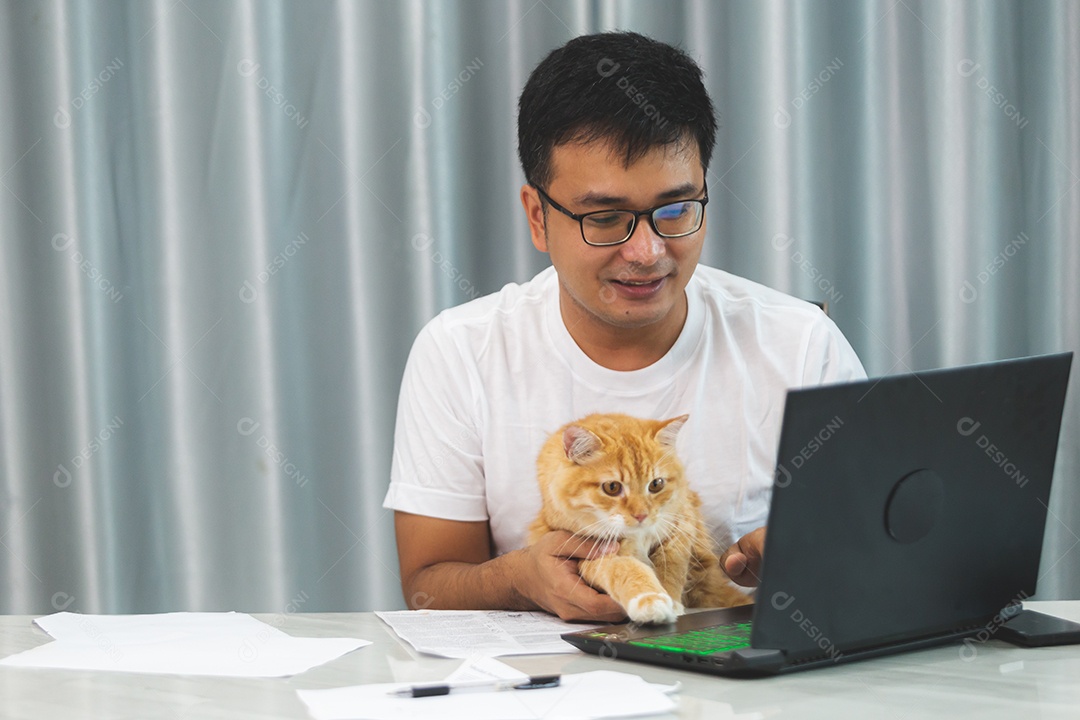 Homem segurando seu gato de estimação sobre escritório mexendo notebook