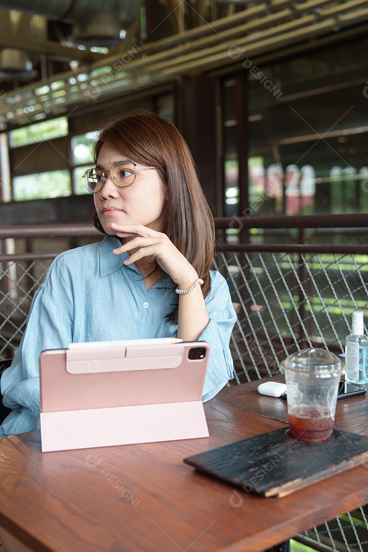 Mulher asiática feliz usando tablet de computador no café