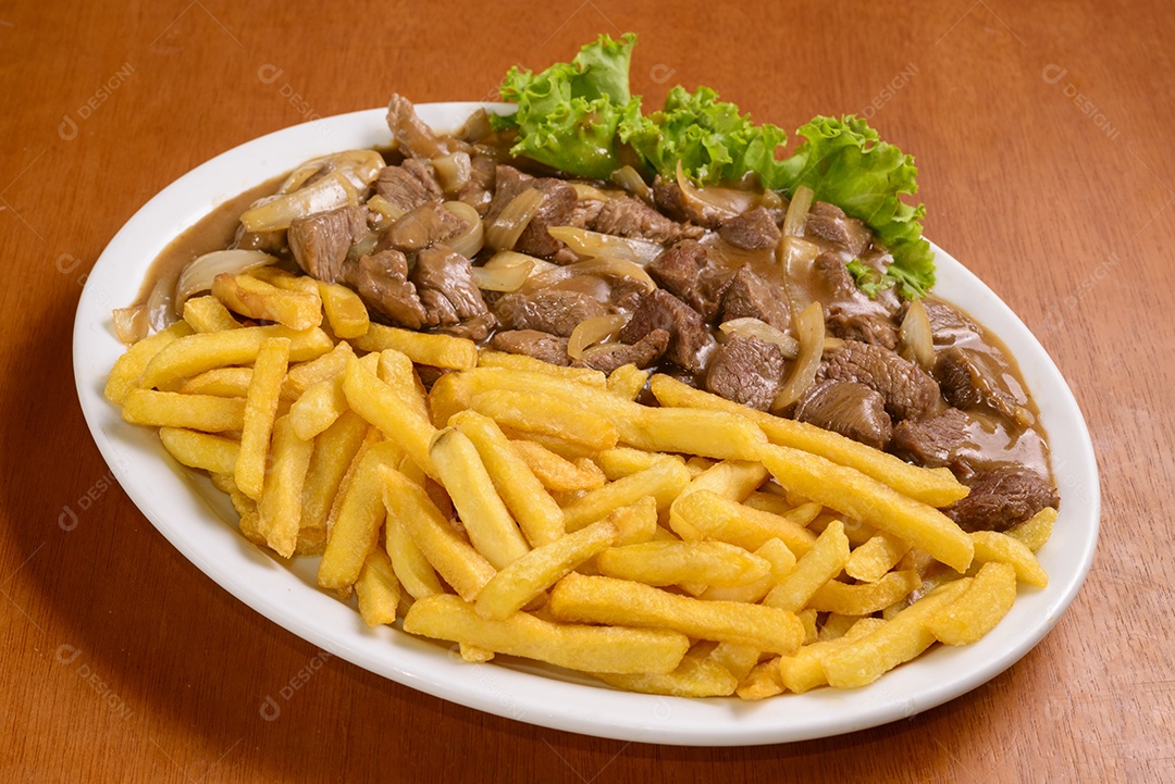 Filé mignon com fritas, servido à moda brasileira na mesa de madeira.
