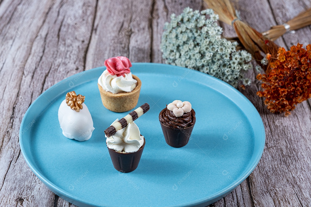 Pequenos doces sofisticados recheados com ganache de chocolate e cobertos com chantilly e fondant.