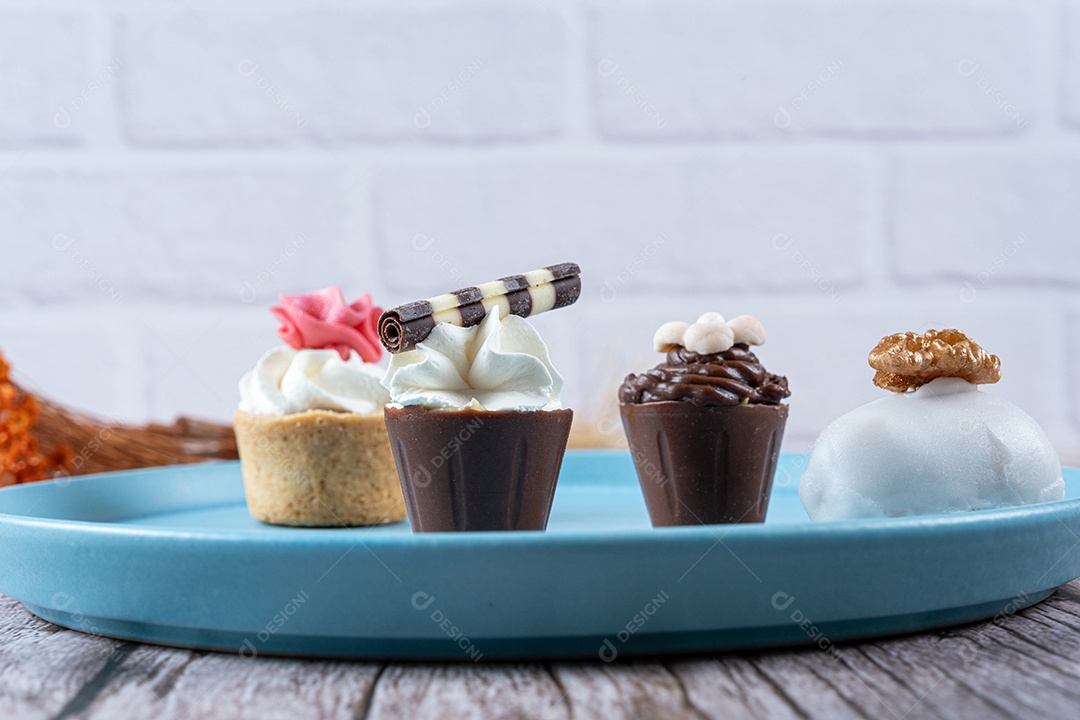 Closeup de quatro pequenos doces extravagantes cheios de ganache de chocolate e chantilly e fondant.