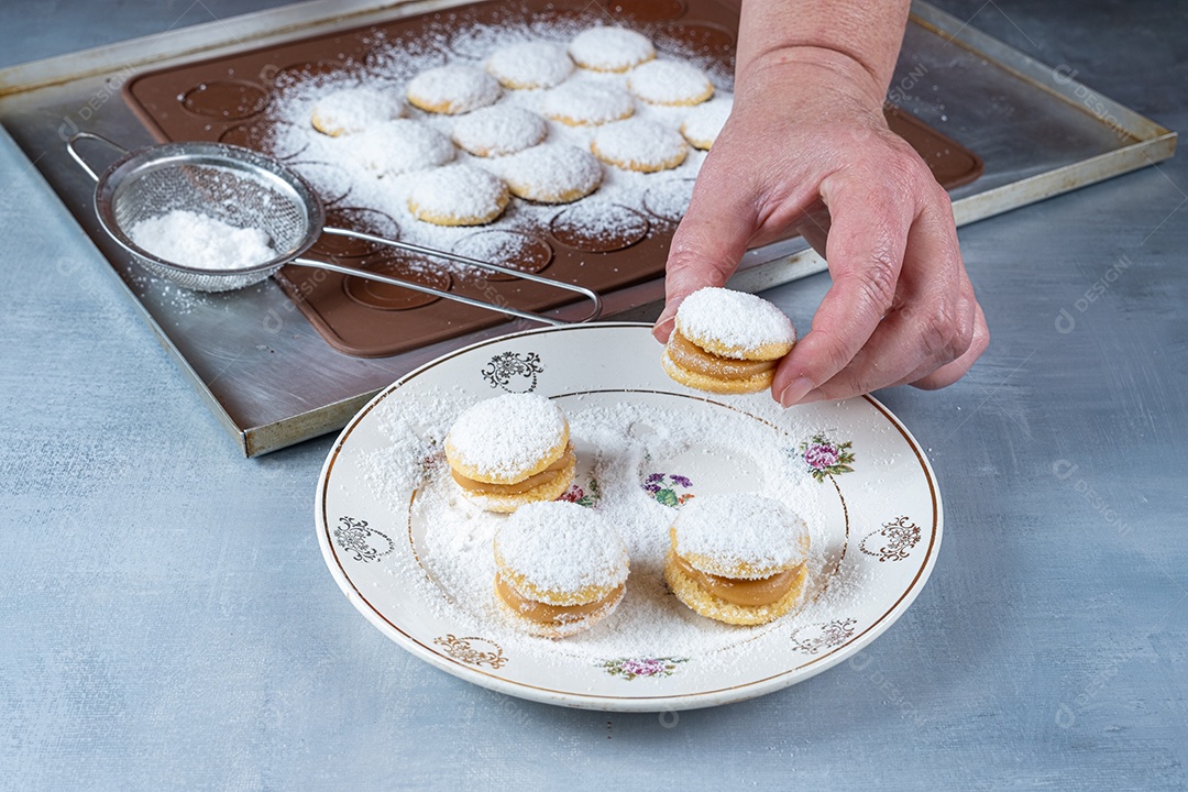 Confeiteiro levando um doce de casamento com açúcar polvilhado e recheio de doce de leite.