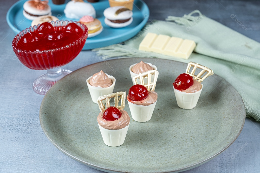 Confeiteira enchendo copinhos de chocolate branco com mousse de chocolate ao leite.