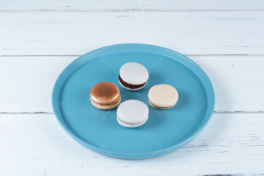 Quatro macarons recheados com ganache de chocolate e doce de leite, em um prato azul.