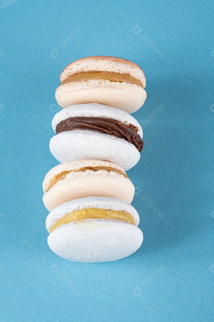 Macarons com recheio de ganache de chocolate e doce de leite empilhados em uma plate_top view azul.