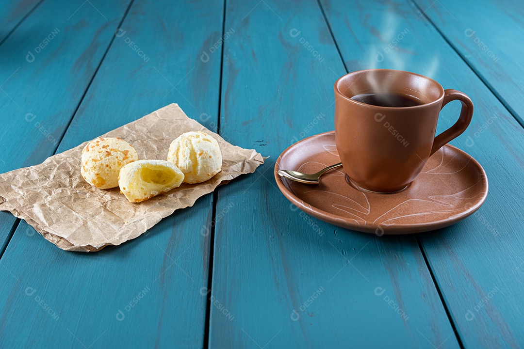Pães de queijo ao lado de xícara de café, colher de cobre e tablet_vertical.