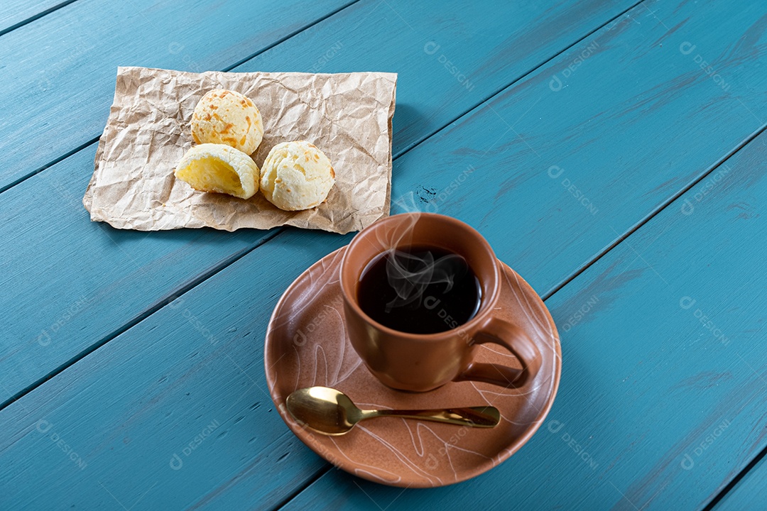 Pães de queijo ao lado de xícara de café, colher de cobre e tablet_vertical.