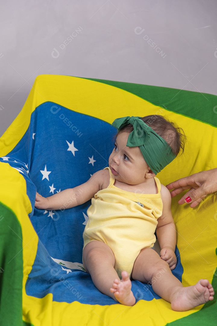 Linda criança bebe sentada sobre fundo bandeira brasil pais