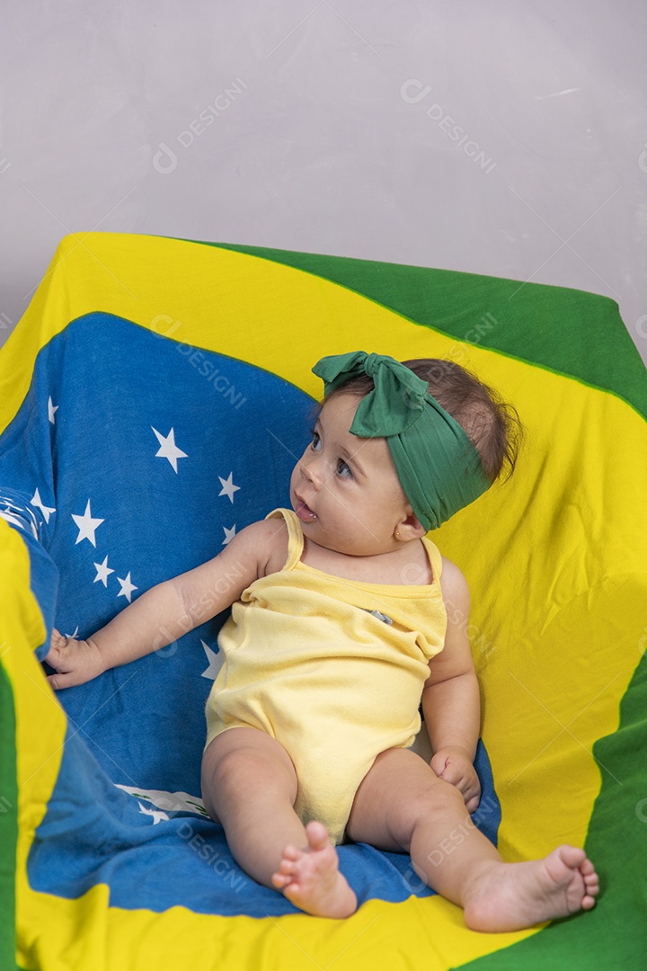 Linda criança bebe sentada sobre fundo bandeira brasil pais
