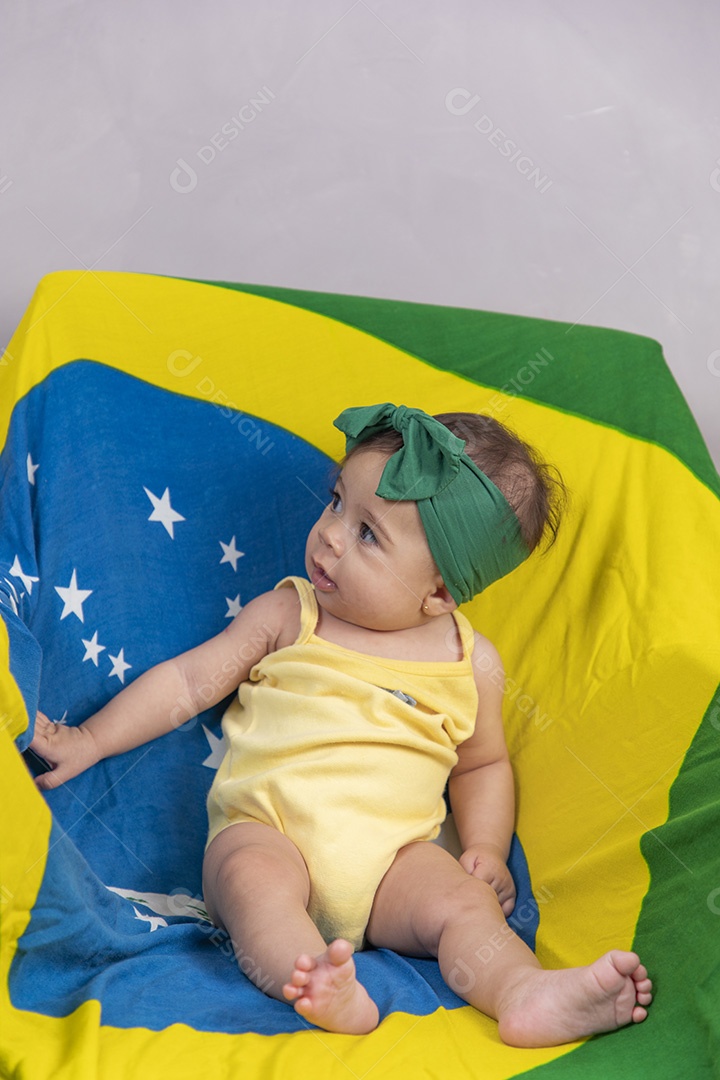 Linda criança bebe sentada sobre fundo bandeira brasil pais