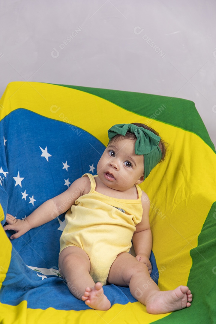 Linda criança bebe sentada sobre fundo bandeira brasil pais