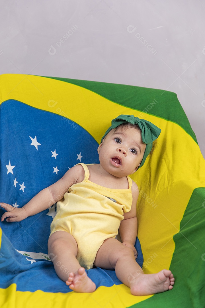 Linda criança bebe sentada sobre fundo bandeira brasil pais