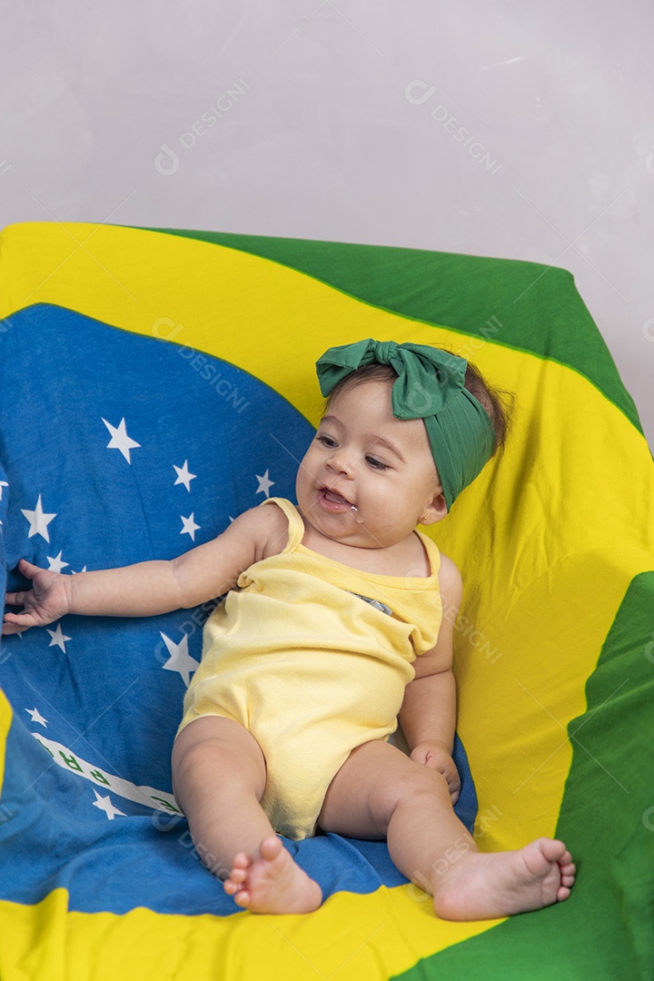 Linda criança bebe sentada sobre fundo bandeira brasil pais