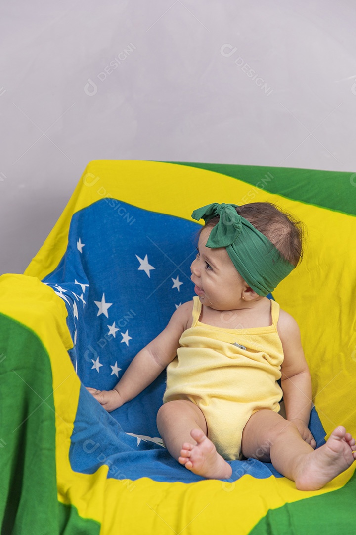 Linda criança bebe sentada sobre fundo bandeira brasil pais