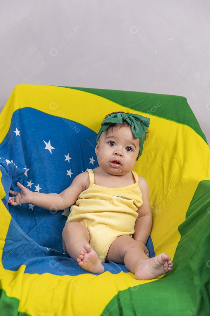 Linda criança bebe sentada sobre fundo bandeira brasil pais