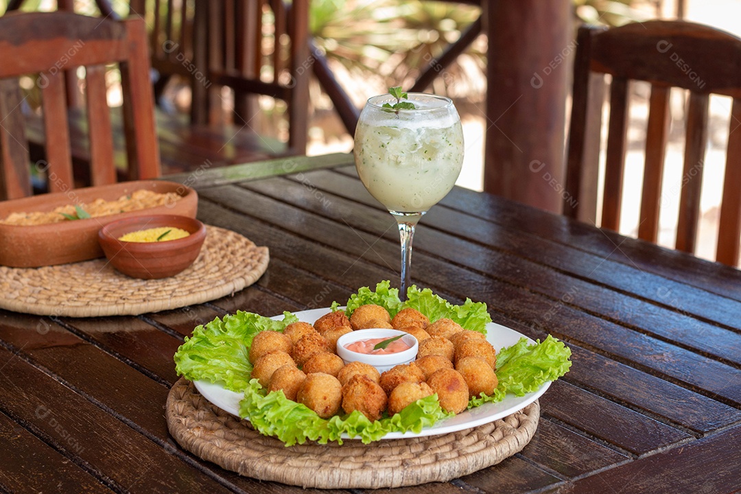 Prato de coxinhas fritas sobre prato branco mesa madeira