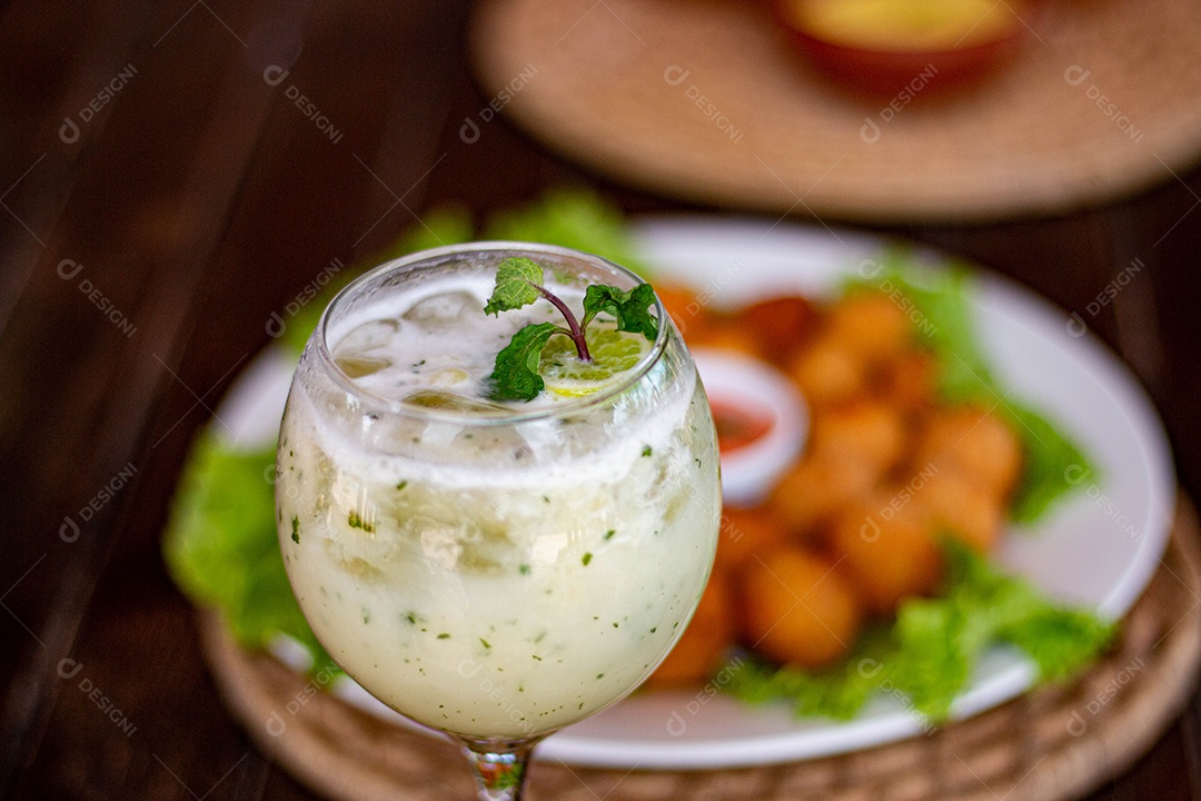 Bebida saborosa sobre taça de vidro sobre um fundo coxinha fritas