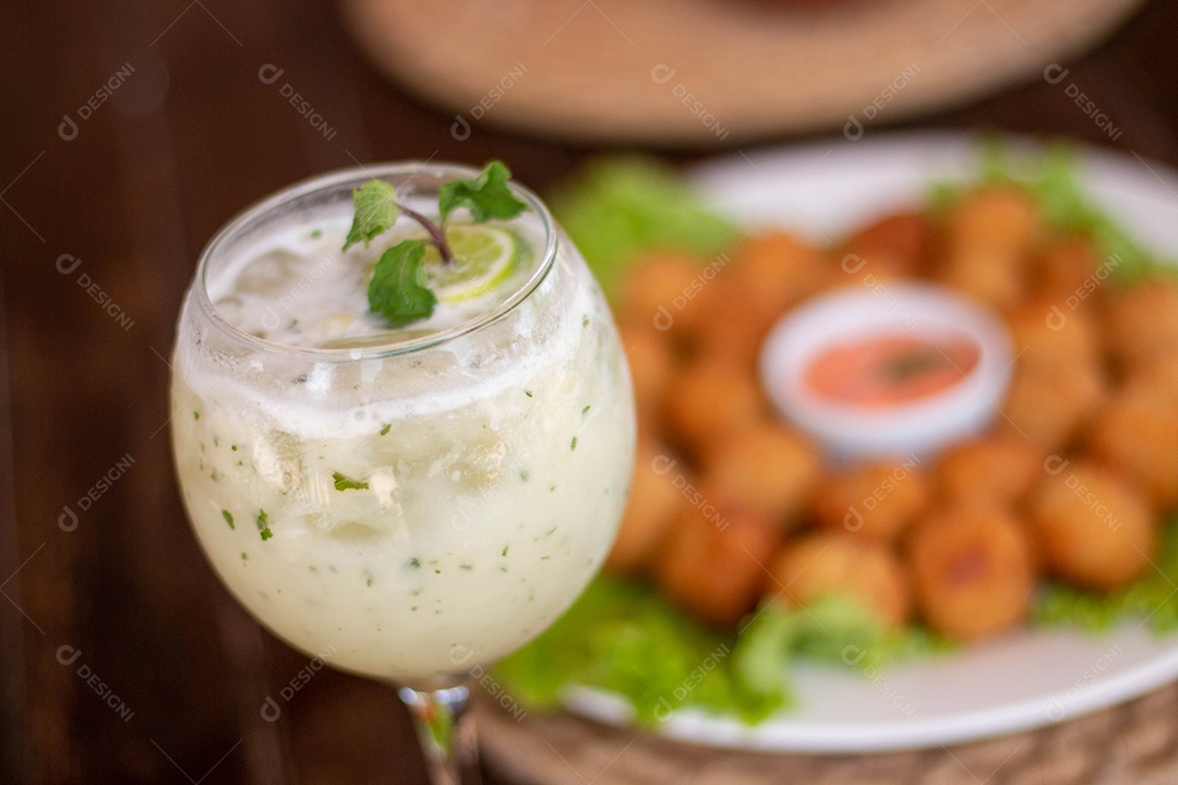 Bebida saborosa sobre taça de vidro sobre um fundo coxinha fritas