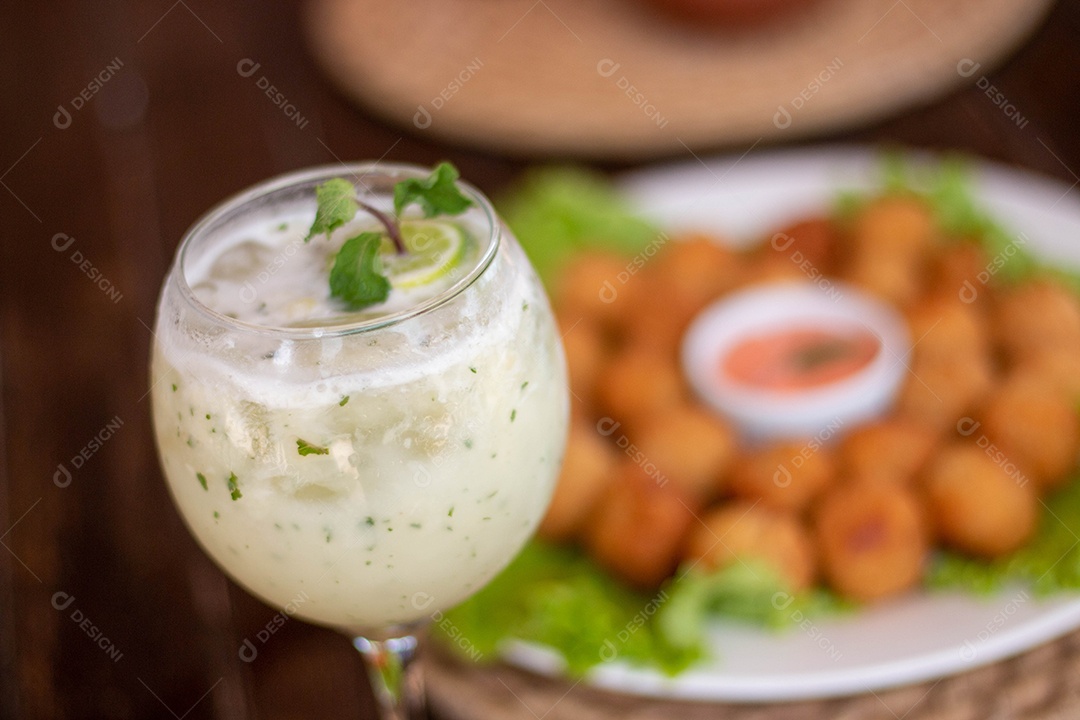 Bebida saborosa sobre taça de vidro sobre um fundo coxinha fritas