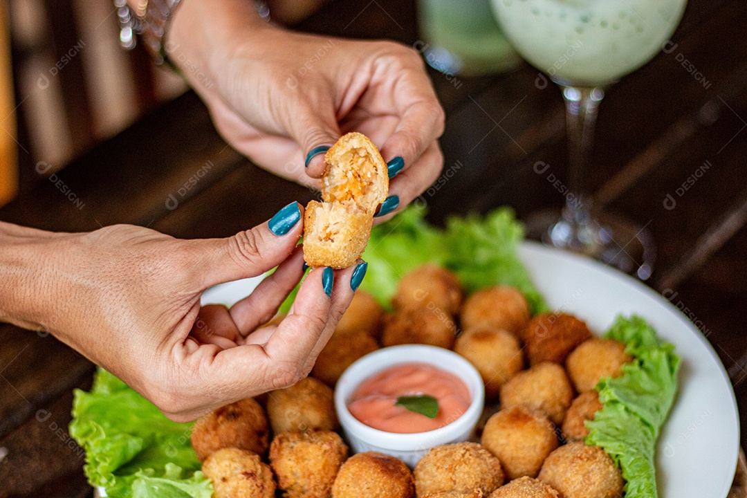 Mãos de pessoa segurando coxinha pequena frita