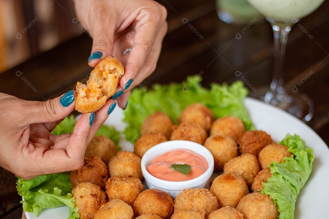 Mãos de pessoa segurando coxinha pequena frita