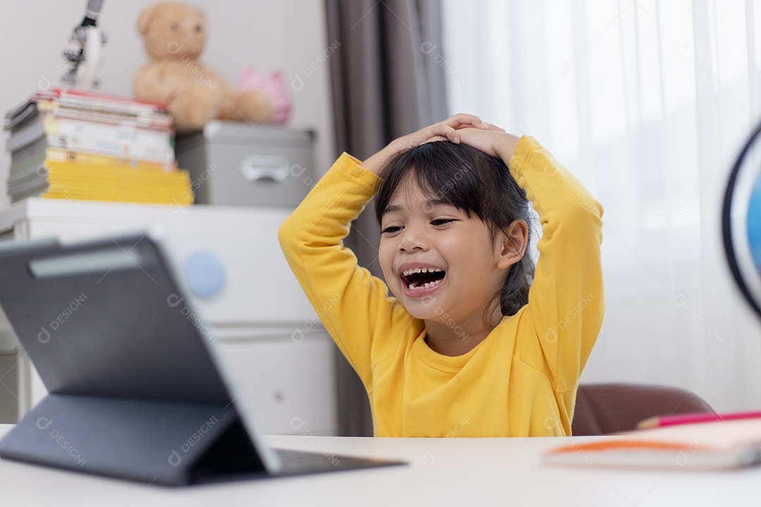 Menina asiática tendo aula on-line e feliz pelo conceito de pandemia de coranavírus de quarentena escolar em casa