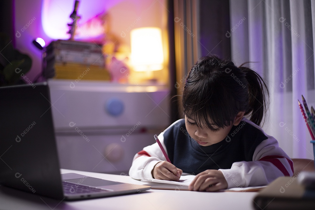 Menina asiática fazendo sua lição de casa com o laptop.