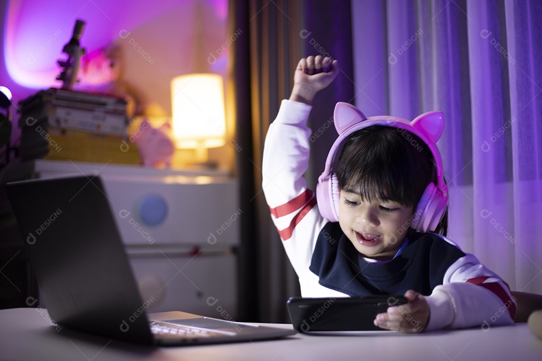 Garota asiática jogando videogame com expressão de vencedor na sala de jogos.