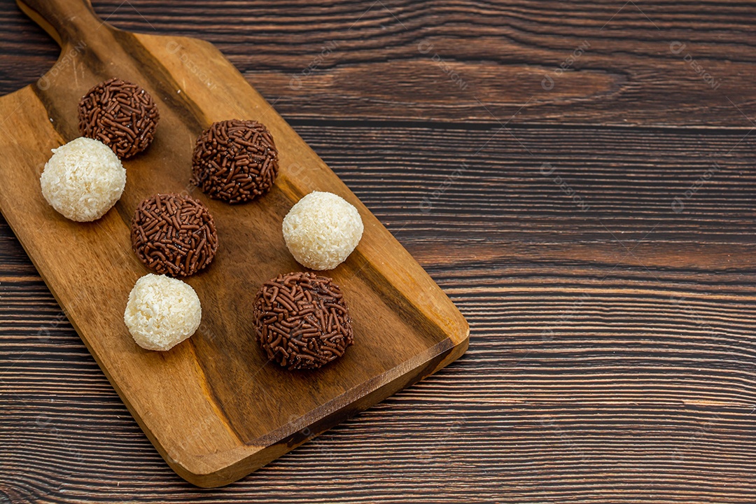 Brigadeiro brasileiro e beijinho tradicional deliciosa sobremesa de chocolate, salgadinhos de festa, fundo de polvilho doce vista superior sobre a mesa de madeira