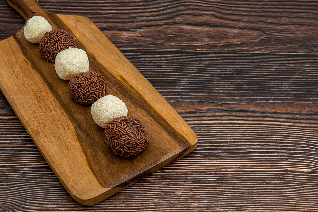 Brigadeiro brasileiro e beijinho tradicional deliciosa sobremesa de chocolate, salgadinhos de festa, fundo de polvilho doce vista superior sobre a mesa de madeira