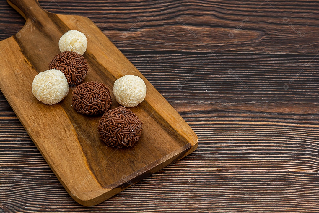 Brigadeiro brasileiro e beijinho tradicional deliciosa sobremesa de chocolate, salgadinhos de festa, fundo de polvilho doce vista superior sobre a mesa de madeira