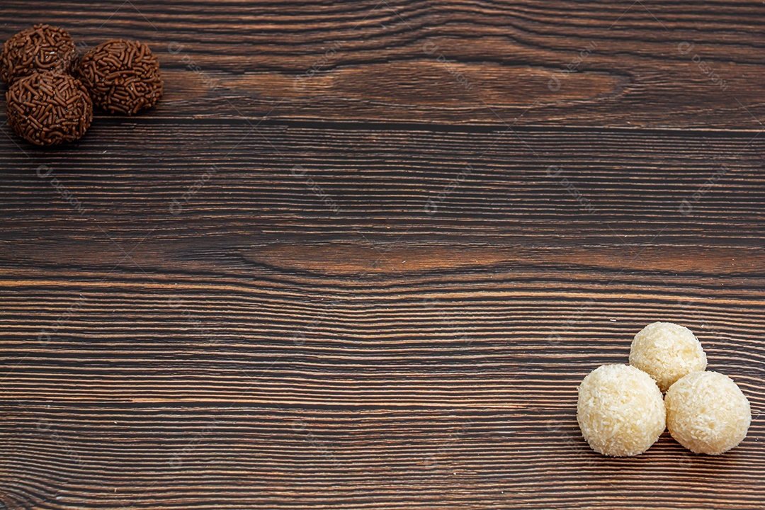 Brigadeiro brasileiro e beijinho tradicional deliciosa sobremesa de chocolate, salgadinhos de festa, fundo de polvilho doce vista superior sobre a mesa de madeira