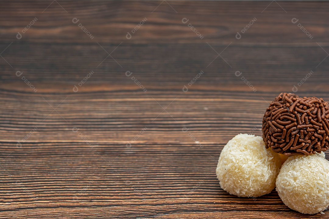 Brigadeiro brasileiro e beijinho tradicional deliciosa sobremesa de chocolate, salgadinhos de festa, fundo de polvilho doce vista superior sobre a mesa de madeira