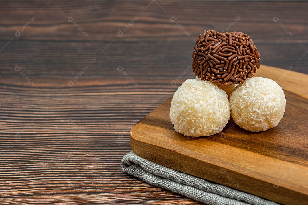 Brigadeiro brasileiro e beijinho tradicional deliciosa sobremesa de chocolate, salgadinhos de festa, fundo de polvilho doce vista superior sobre a mesa de madeira