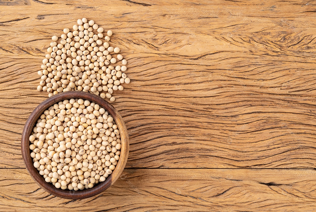 Grãos de soja crus em uma tigela sobre a mesa de madeira com espaço de cópia.