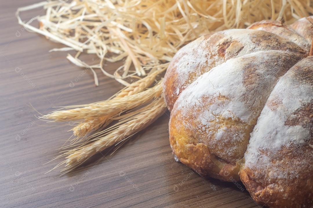 Pão de abóbora feito em forma de abóbora em uma mesa de madeira.