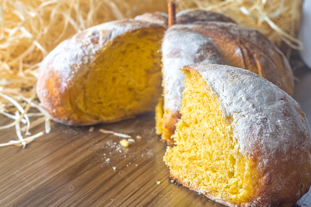 Pão de abóbora feito em forma de abóbora em uma mesa de madeira.