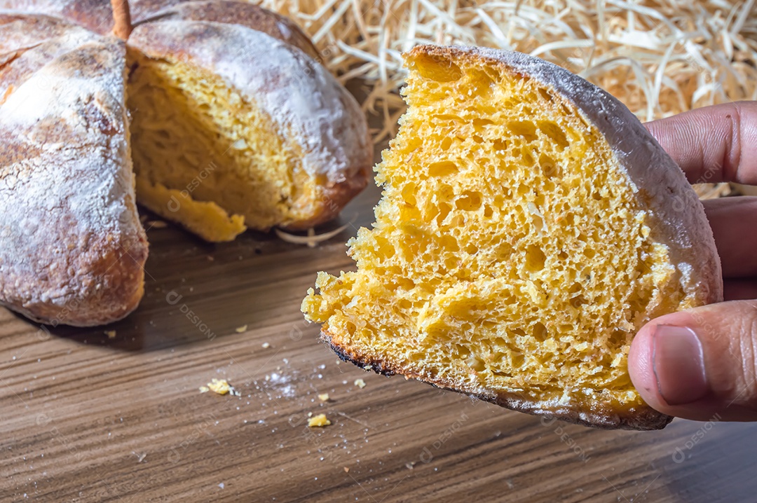 Pão de abóbora feito em forma de abóbora em uma mesa de madeira.