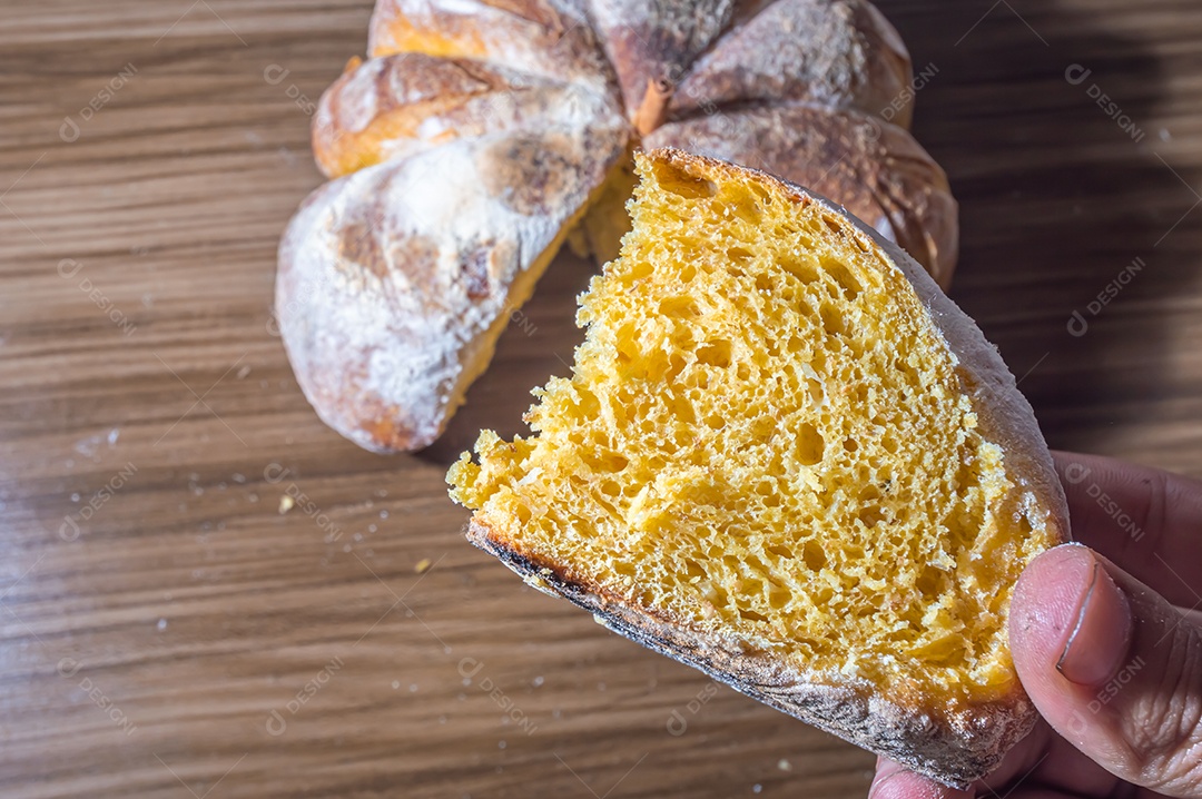 Pão de abóbora feito em forma de abóbora em uma mesa de madeira.