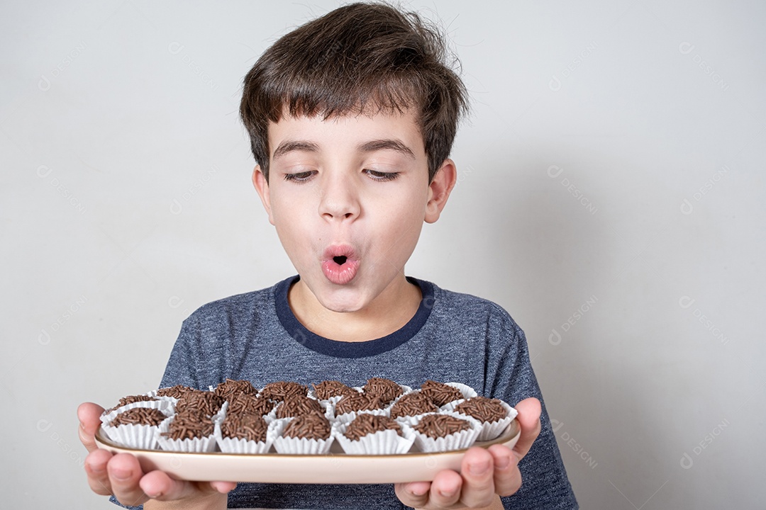 Brasileiro de 9 anos olhando para uma bandeja com várias bolas de chocolate brasileiras e parecendo surpreso.