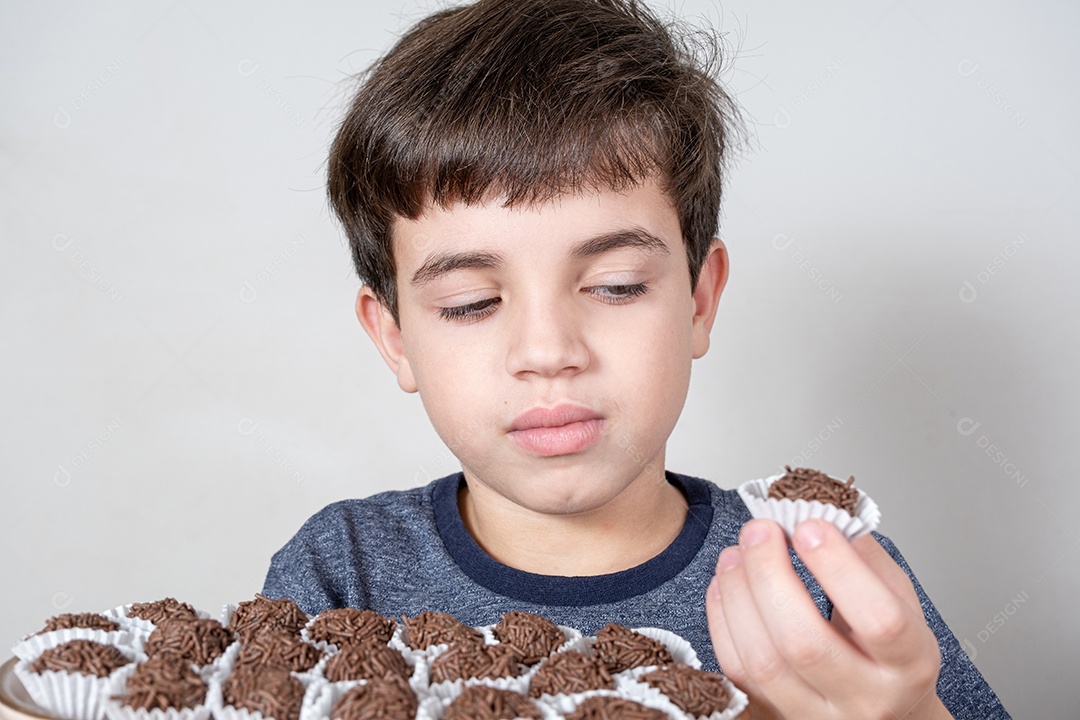Brasileiro de 9 anos olhando desconfiado para uma bola de chocolate brasileira.