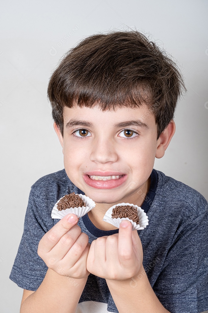 Brasileiro de 9 anos sorrindo e segurando duas bolas de chocolate brasileiras.