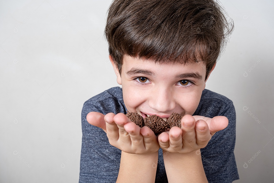 9 anos segurando três bolas de chocolate brasileiras e sorrindo