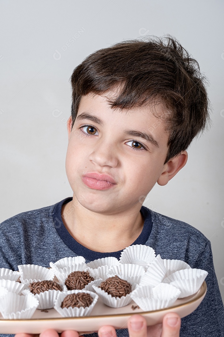 Brasileiro de 9 anos olhando desconfiado para uma bola de chocolate brasileira.